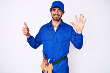 Kıvırcık saçlı ve ayı gibi giyinen yakışıklı genç adam altı numarayı gösterip işaret ederken kendinden emin ve mutlu gülümsüyor.. 