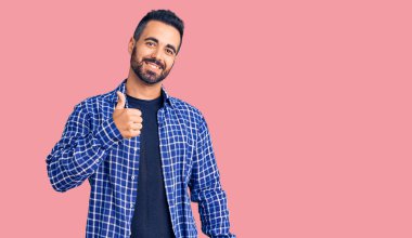 Gündelik kıyafetler giyen genç İspanyol adam elleriyle mutlu bir jest yapıyor. Kameraya bakıp başarıyı gösteren ifade. 