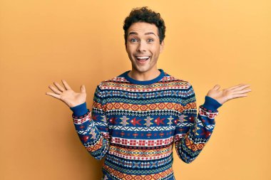 Kış süveteri giyen genç yakışıklı adam zaferi mutlu bir gülümsemeyle ve kazanan yüz ifadesiyle kutluyor. 