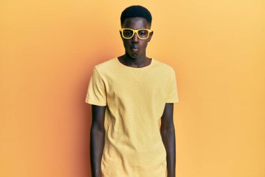 Gündelik kıyafetler ve gözlük takan genç Afro-Amerikan adam dudaklarıyla balık suratı yapıyor, çılgınca ve komik bir jest. Komik ifade. 