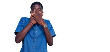 Gündelik giysiler giyen genç Afro-Amerikan bir adam yanlışlıkla elleri ile ağzını kapatırken şok oldu. gizli kavram. 