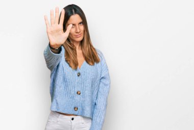 Günlük kıyafetler giyen genç bir kadın avucunun içi gibi şarkı söylemeyi kesiyor. Yüzünde olumsuz ve ciddi bir jest olan uyarı ifadesi. 