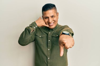 Gündelik kıyafetler giyen, gülümseyen, telefonda konuşan ve seni işaret eden genç latin adam. Ara beni.. 