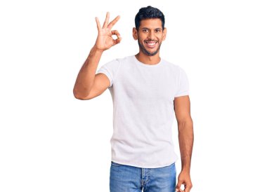 Gündelik kıyafetler giyen, gülümseyen genç latin adam el ve parmaklarıyla 