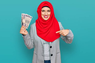 Güzel İspanyol kadın, elinde Japon yen banknotlarıyla mutlu ve gururlu bir şekilde gülümseyen birini işaret ediyor. 