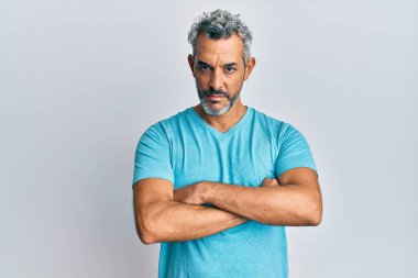 Orta yaşlı, gri saçlı, sıradan kıyafetler giyen şüpheci ve gergin, yüzünde çapraz kollu tasvip etmeyen bir ifade. negatif kişi. 