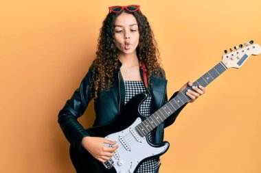 Elektro gitar çalan genç İspanyol kız ağzıyla balık suratlı ve şaşı gözlü, çılgın ve komik.. 