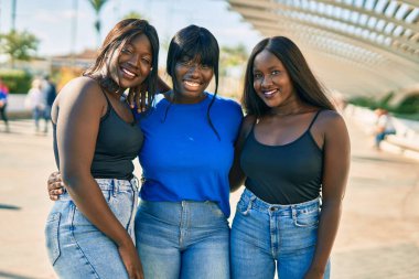 Üç Afrikalı Amerikalı arkadaş gülümsüyor. Mutlu bir şekilde kucaklaşıyorlar..