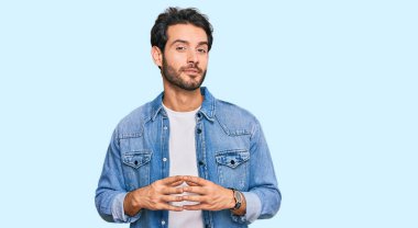 Latin asıllı genç adam rahat ve neşeli gülümseyerek ellerini birleştirip gülümsedi. Başarı ve iyimserlik 