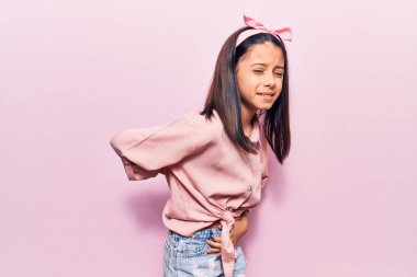 Güzel bir kız çocuğu gündelik kıyafetler giyiyor sırt ağrısı çekiyor, elleriyle dokunuyor, kas ağrısı çekiyor. 