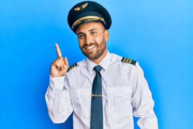 Sakallı, uçak pilotu üniforması giyen yakışıklı bir numaralı parmağını gösterip gösterirken kendinden emin ve mutlu bir şekilde gülümsüyor.. 