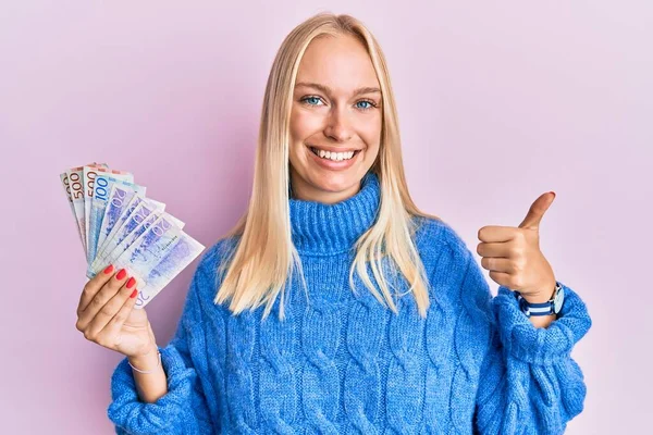 Mladá Blondýnka Drží Švédské Koruny Bankovky Úsměvem Šťastný Pozitivní Palec — Stock fotografie