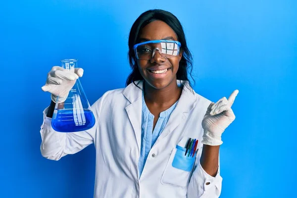 若いですアフリカ系アメリカ人女性身に着けています科学者制服保持テストチューブ笑顔幸せなポインティングとともに手と指で側面 — ストック写真