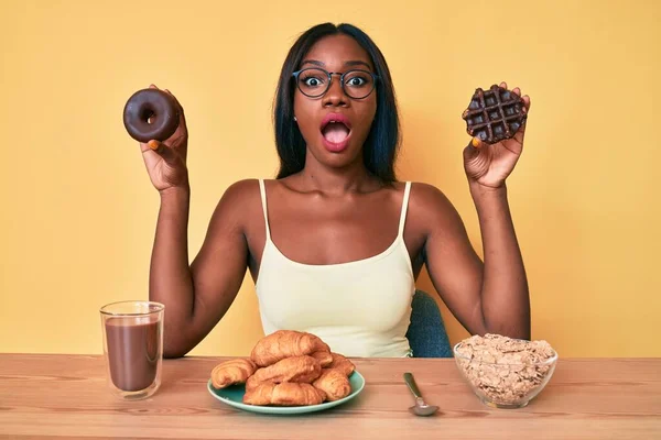 Młoda Afroamerykanka Trzymająca Czekoladowego Pączka Gofra Śniadanie Przerażona Zszokowana Zaskakującą — Zdjęcie stockowe