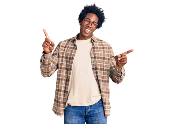 英俊的非洲裔美国男人 留着黑头发 穿着休闲装 戴着眼镜 自信地微笑着 手指指向不同的方向 复制广告空间 — 图库照片