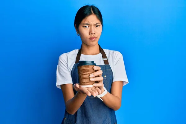 Mujer Joven China Con Delantal Camarero Sosteniendo Taza Café Escéptico —  Fotos de Stock