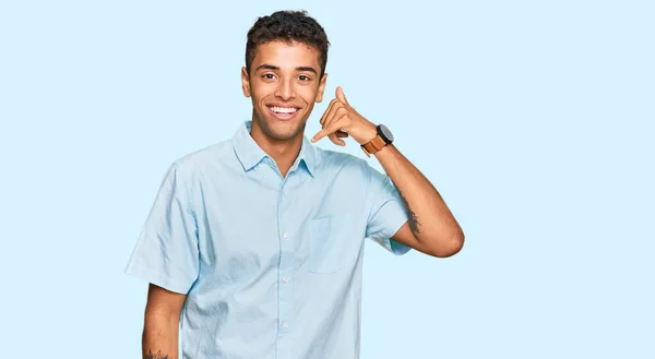年轻英俊的非洲裔美国男人穿着休闲装 微笑着用手和手指做着电话手势 就像在电话里说话一样 交流概念 — 图库照片