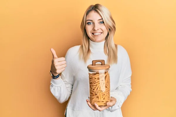 Joven Mujer Caucásica Sosteniendo Tarro Pasta Macarrones Sonriendo Feliz Positivo —  Fotos de Stock