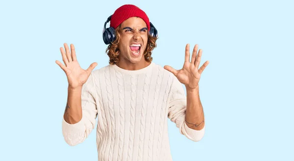 Young Hispanic Man Listening Music Using Headphones Crazy Mad Shouting — Stock Photo, Image