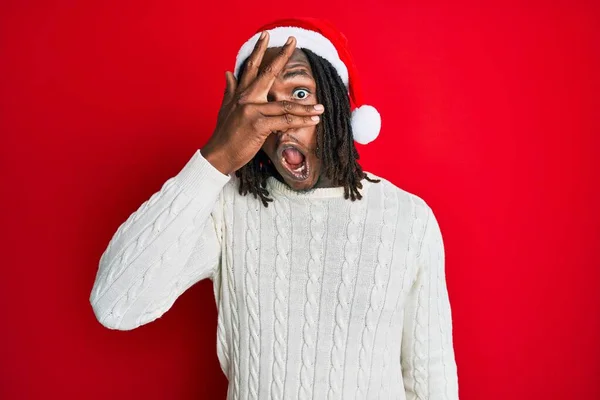 Africano Americano Com Tranças Vestindo Chapéu Natal Espreitando Choque Cobrindo — Fotografia de Stock
