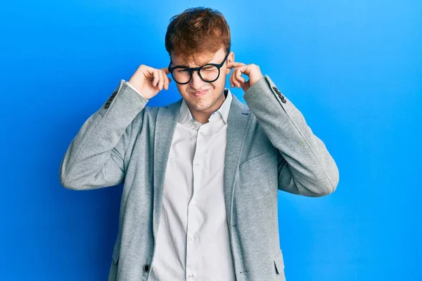 エレガントな服を着た若い白人男性と 大きな音楽のノイズのためにいらいらする表情で指で耳を覆う眼鏡 聴覚障害の概念 — ストック写真