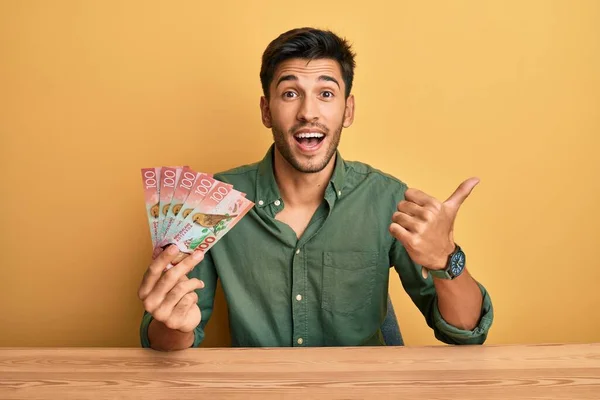 Joven Hombre Guapo Sosteniendo 100 Billetes Nuevos Zealand Dólares Apuntando —  Fotos de Stock