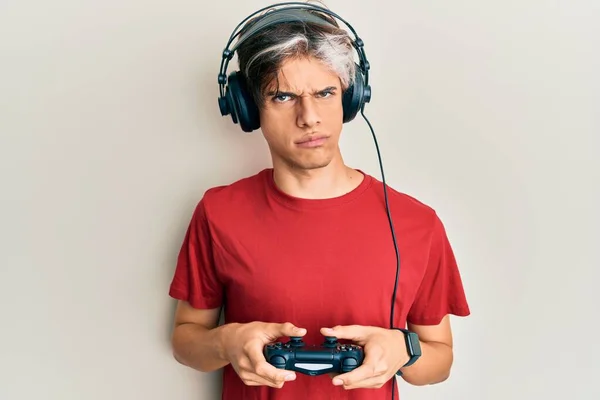 Joven Hombre Hispano Jugando Videojuego Sosteniendo Controlador Escéptico Nervioso Frunciendo —  Fotos de Stock