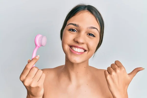 Young Brunette Woman Using Facial Exfoliating Brush Pointing Thumb Side — Stock Photo, Image