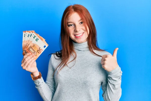 Joven Chica Pelirroja Sosteniendo Manojo Billetes Euros Sonriendo Feliz Positivo — Foto de Stock