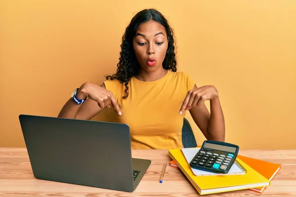 Młoda Afroamerykanka Pracująca Biurze Laptopem Kalkulatorem Wskazującym Palcami Pokazującymi Reklamę — Zdjęcie stockowe