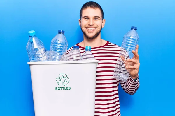 若いですハンサムな男リサイクルプラスチックボトル正と幸せな立ちと笑顔で自信を持って笑顔を示す歯 — ストック写真