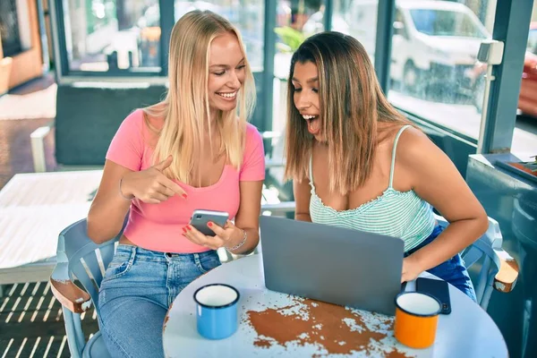 两个年轻漂亮的女朋友在自助餐厅用笔记本电脑和智能手机相遇 — 图库照片