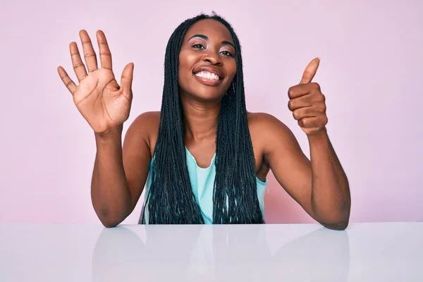 Afroamerikanerin Mit Zöpfen Lässiger Kleidung Sitzt Auf Dem Tisch Und — Stockfoto