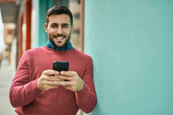 Joven Hombre Hispano Sonriendo Feliz Usando Smartphone Ciudad —  Fotos de Stock