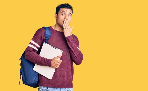 Joven Joven Guapo Hispano Con Mochila Estudiante Cuaderno Cubriendo Boca —  Fotos de Stock