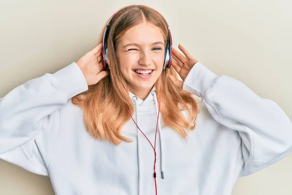 Hermosa Chica Caucásica Joven Escuchando Música Usando Auriculares Guiñando Ojo — Foto de Stock