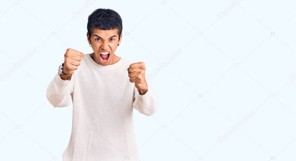 Young african amercian man wearing casual clothes angry and mad raising fists frustrated and furious while shouting with anger. rage and aggressive concept. 