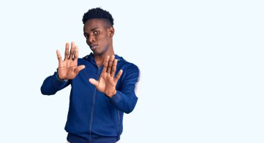Genç Afro-Amerikan erkek spor giysisi giyiyor. Avuçlarını hareket ettiriyor. Korkmuş ve iğrenç bir ifadeyle reddediyor. Dur ve yasakla. 