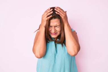 Orta yaşlı esmer, günlük kıyafetler giyen, baş ağrısı çeken çaresiz ve stresli bir kadın. Çünkü acı ve migren ağrısı var. Eller başının üstünde.. 