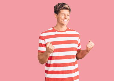 Başarılı olmak için heyecanlı, kolları havada ve gözleri kapalı gülümseyerek zaferi kutlayan gündelik giysiler giyen genç yakışıklı bir adam. Kazanan konsept. 