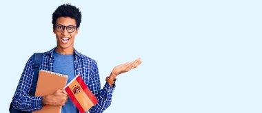 Afrika kökenli Amerikalı genç bir adam sırt çantasıyla İspanyol bayrağı taşıyor zaferi mutlu bir gülümsemeyle kutluyor ve kazanan ifade ellerini kaldırıyor. 