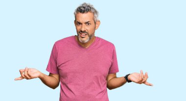 Orta yaşlı, gri saçlı, sıradan kıyafetler giyen, kolları açık ve kafası karışık bir adam.. 