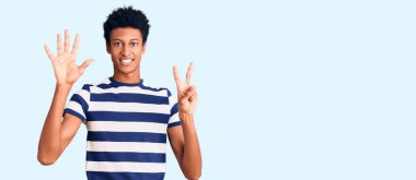 Genç Afro-Amerikalı günlük giysiler giymiş yedi numarayı gösterip işaret ederken kendinden emin ve mutlu bir şekilde gülümsüyor.. 