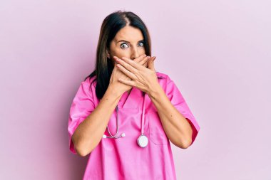 Orta yaşlı esmer kadın doktor üniforması giyiyor ve steteskop yanlışlıkla ağzı ellerle kapatıyor. gizli kavram. 