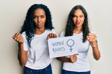 Afrika kökenli Amerikalı anne ve kız ellerinde kadın hakları afişi kızgınlıkla bağırıyor, öfkeyle bağırıyor ve el kaldırıyor. 