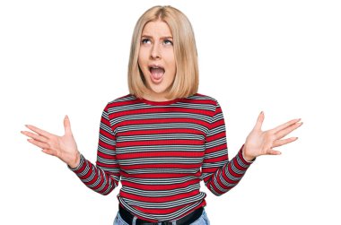 Sıradan kıyafetler giyen genç sarışın kadın deli gibi bağırıyor ve agresif bir ifadeyle bağırıyor ve kollarını kaldırıyor. hüsran kavramı. 