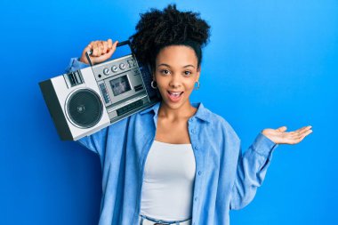 Genç Afrikalı Amerikalı kız elinde teyp ile başarıyı mutlu bir gülümsemeyle ve kazanan ifadeyle kutlayan müzik dinliyor. 