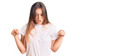 Güzel, beyaz tişört giyen beyaz bir kadın parmaklarını göstererek reklamını yapıyor, şaşırmış bir yüz ve açık bir ağız. 