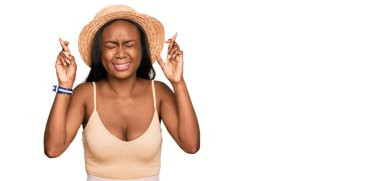 Yazlık şapkalı genç siyahi kadın umut ve gözlerin kapalı bir şekilde gülümseyerek bana işaret etti. Şans ve batıl inançlar. 