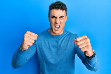 Hispanik genç adam öfkeyle bağırırken kızgın ve kızgın yumruk kaldırıyor. öfke ve agresif konsept. 